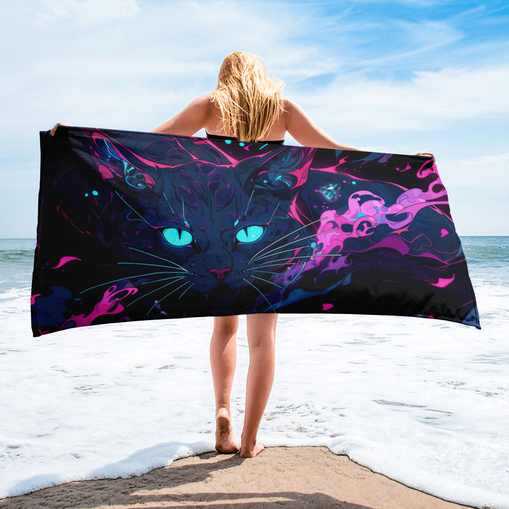 Person holding a colorful towel with a cat design on a beach